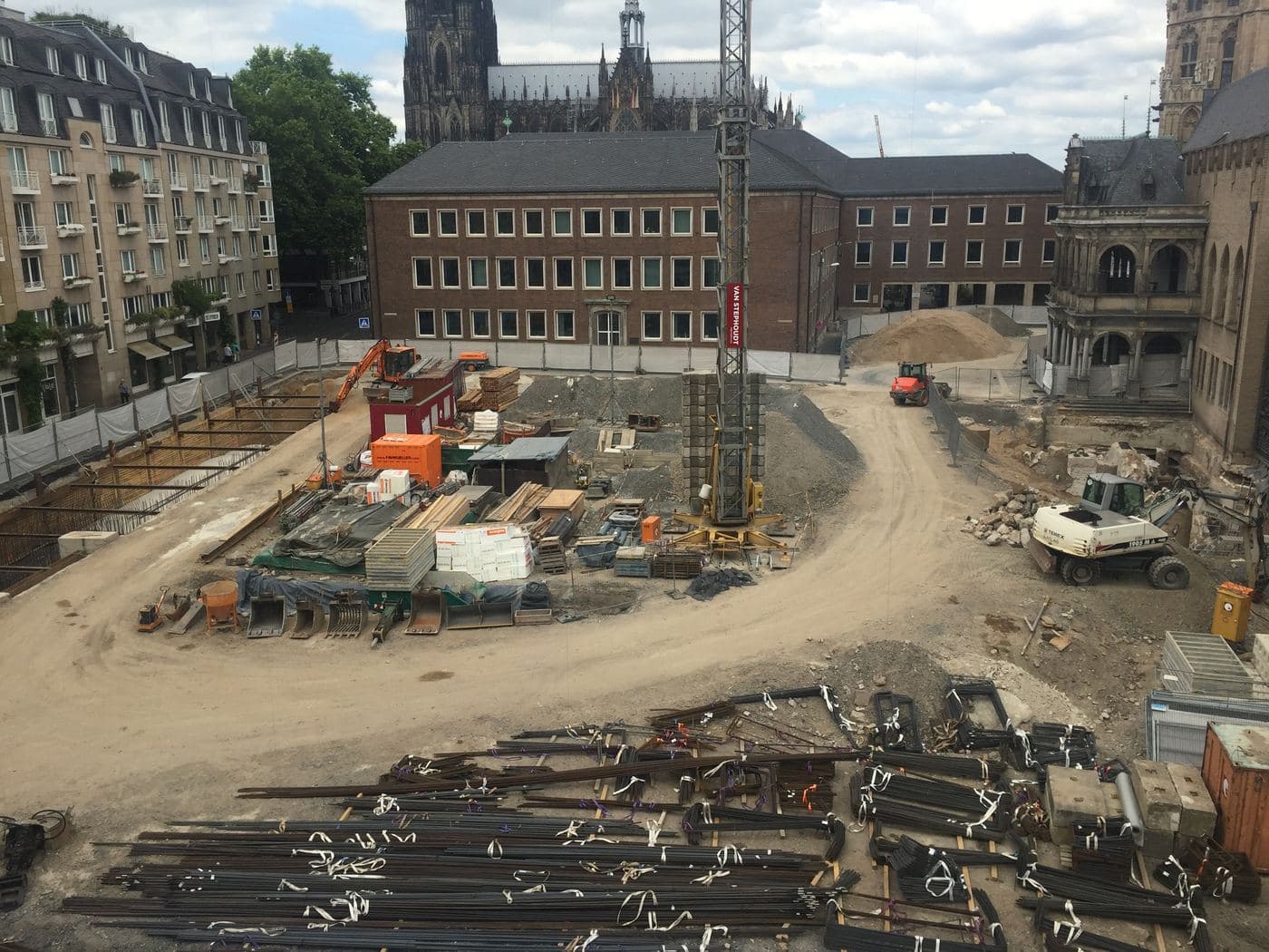 Aerial view of a construction site with rebar, excavators and a tower crane