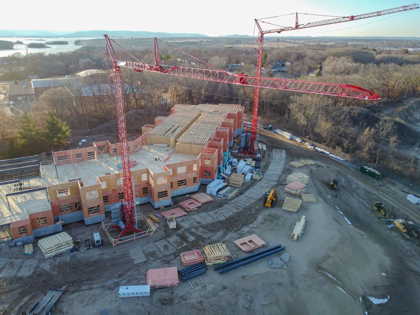 Tower cranes over a timber-framed building under construction