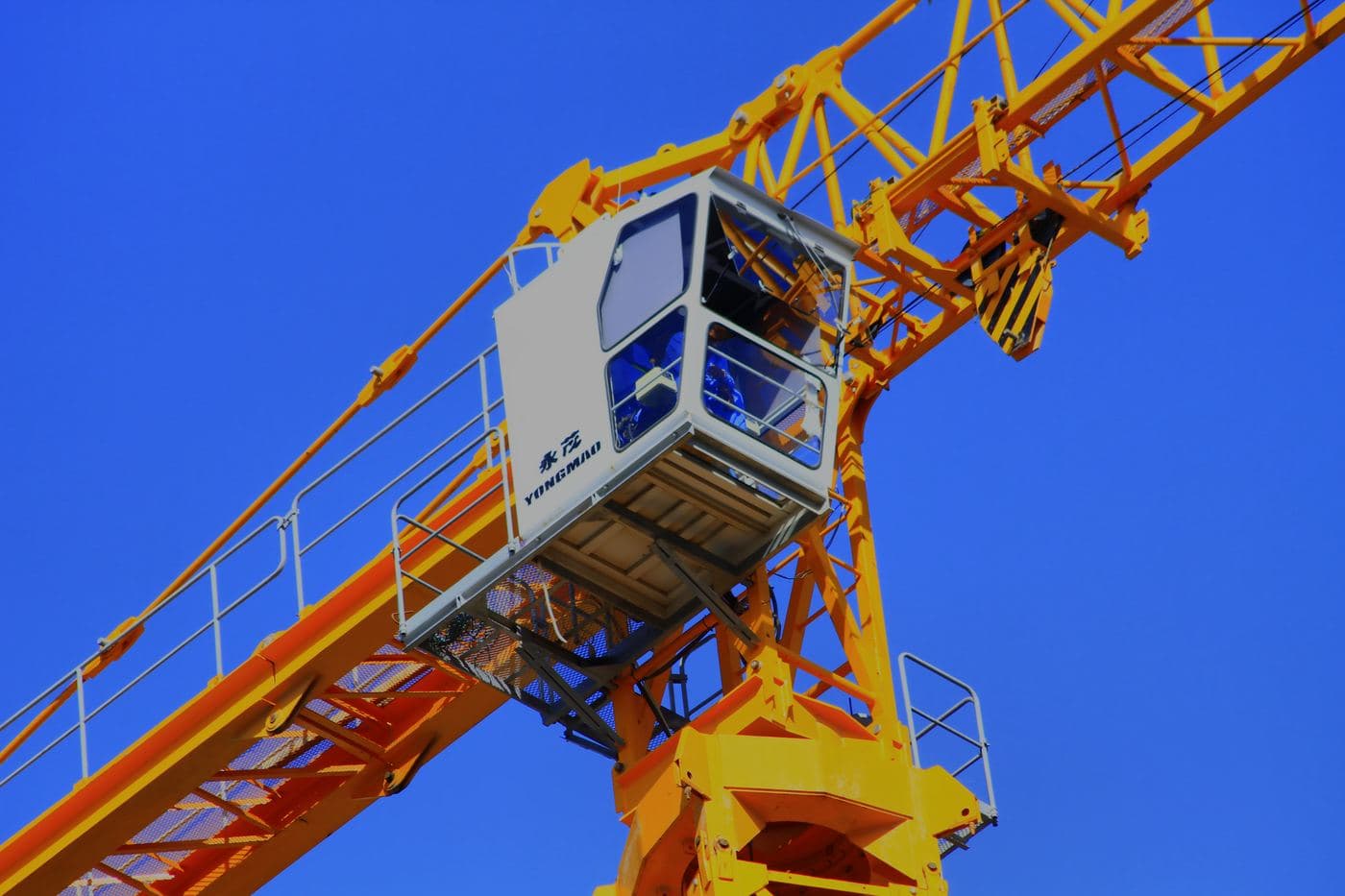 Close-up of a tower crane cabin against a clear blue sky